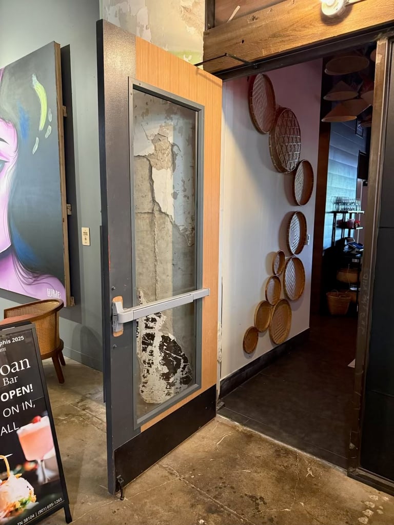 Modern art gallery entrance with concrete floors, featuring an open doorway displaying sculptural elements and wooden woven rings on the interior wall
