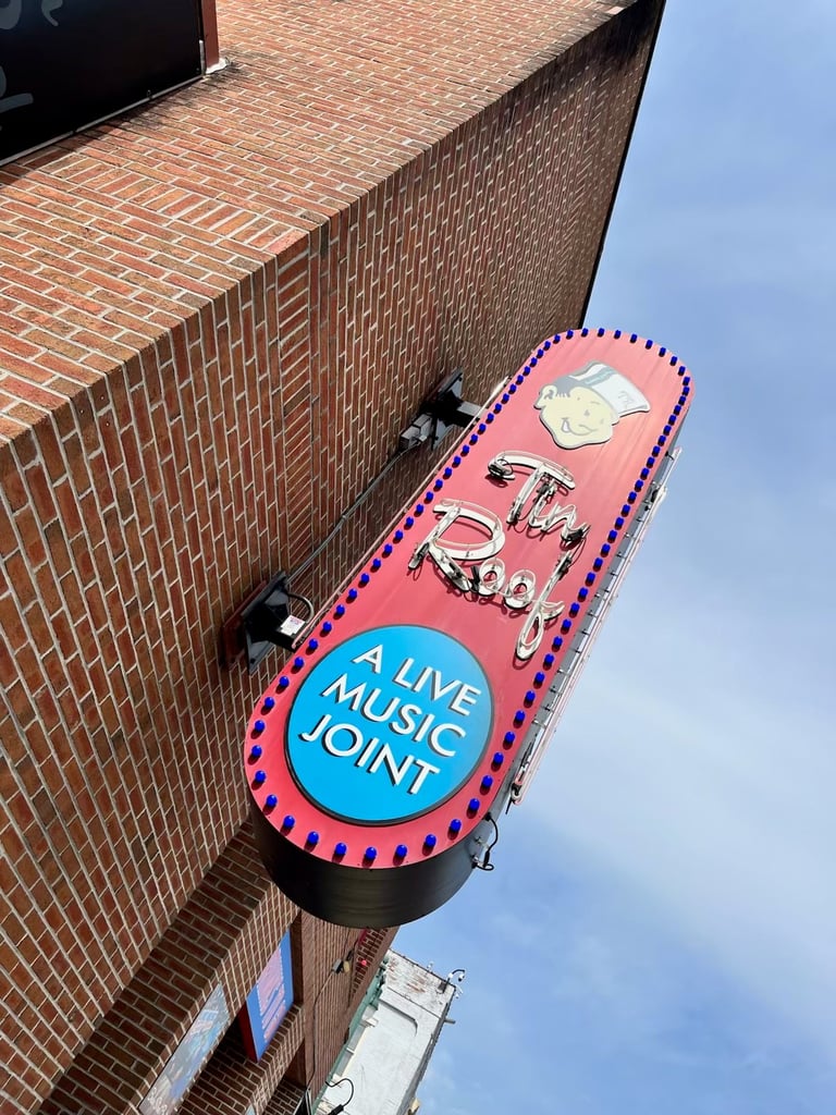 Neon pink and blue live music joint sign mounted on brick building wall